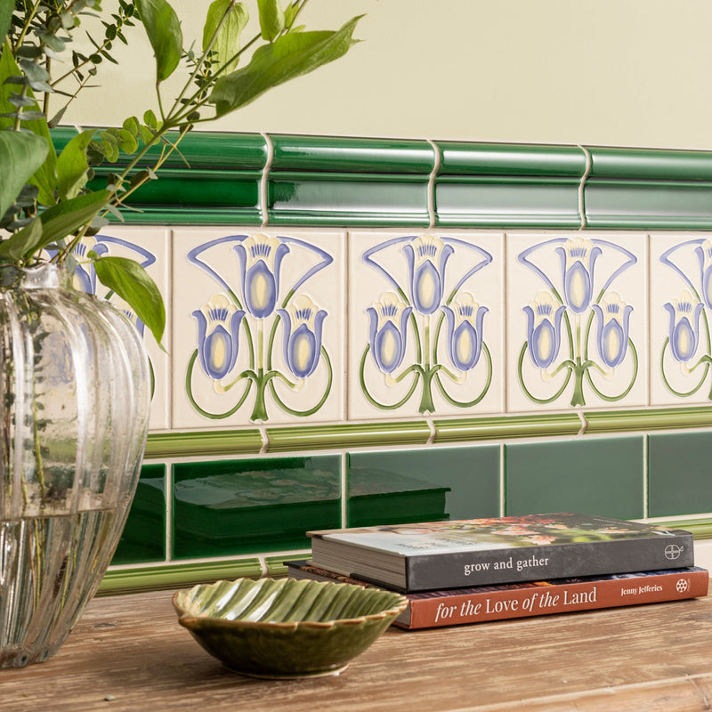 Green and white ceramic liberty decorative tubelined tile with repeating art nouveau floral pattern in purple and green