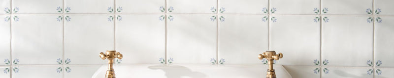 Gold-toned ornate faucet handles with intricate detailing on a white tiled surface from original style spring tiles collection