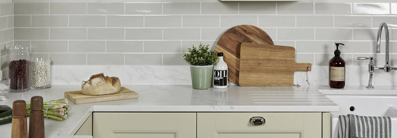 A rustic wooden cutting board with natural wood grain and curved edge from the Alhambra collection resting on countertop