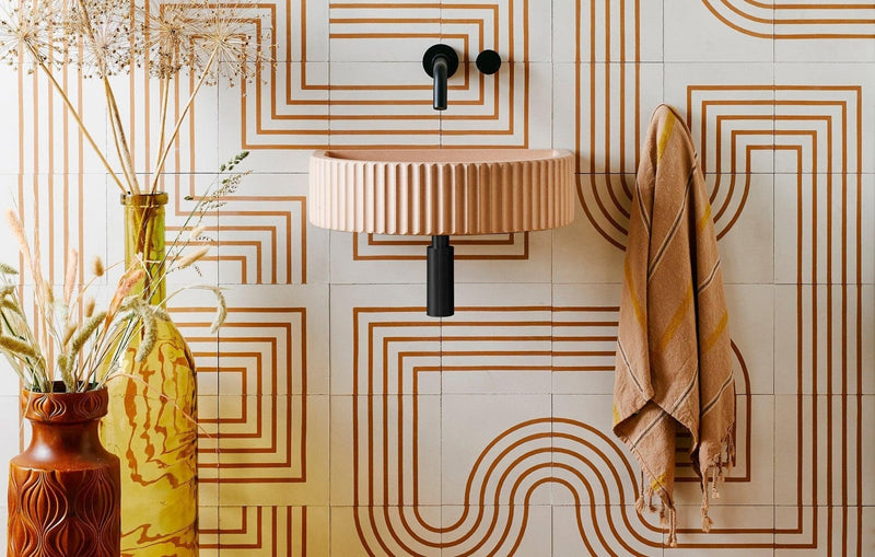Beige ribbed ceramic wall-mounted sink with black faucet and pipe in luxury tiles and flooring collection.