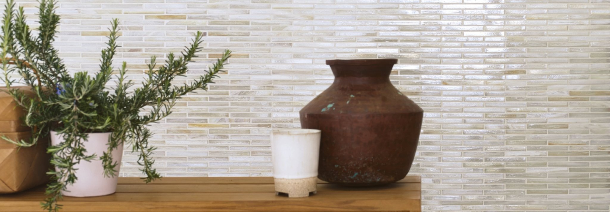 A rustic brown ceramic vase with a wide rounded body and flared rim on a wooden surface in Arabian Sea Glass Mosaics.