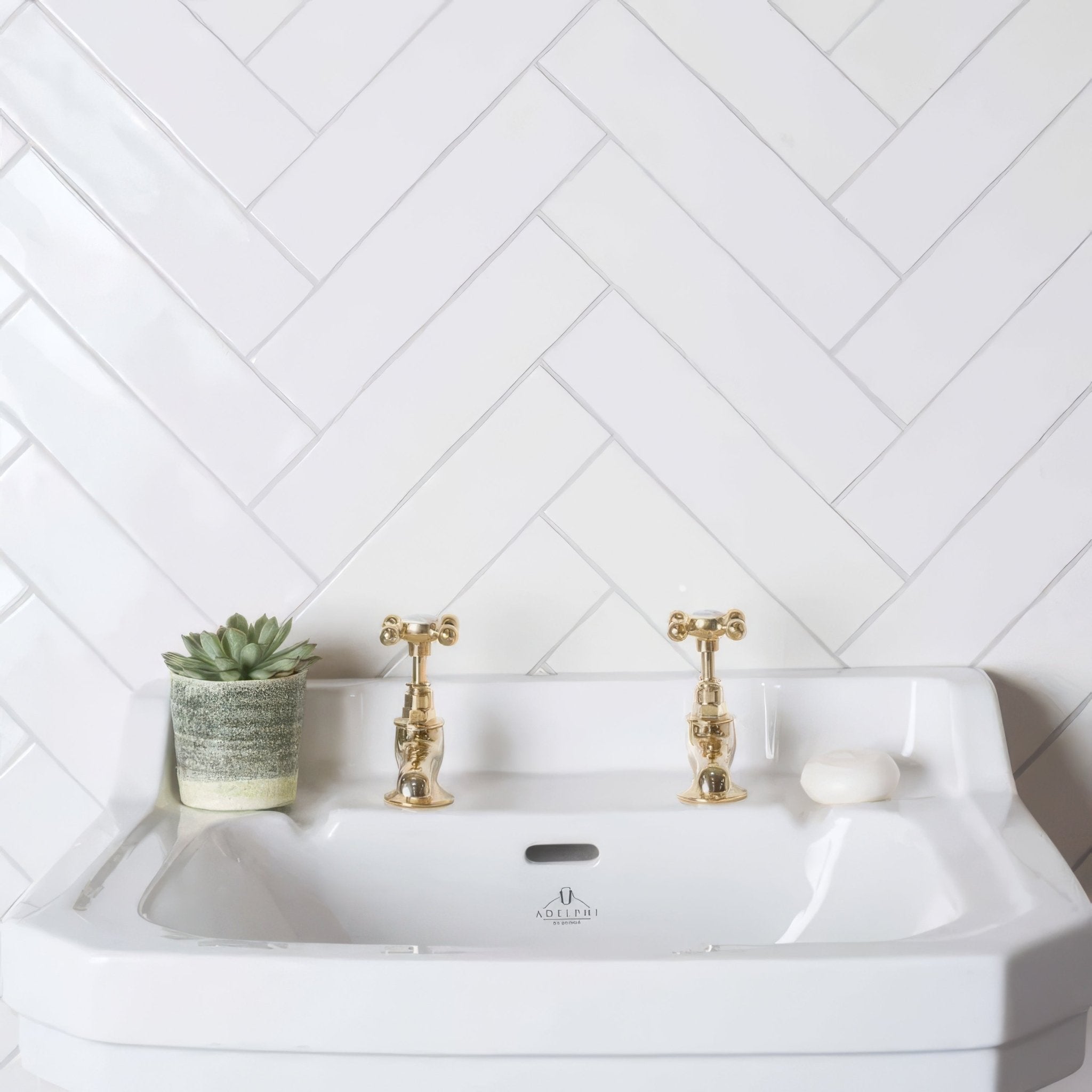 White ceramic sink with gold-toned cross-handle faucets and subtle logo in the Arcadian 300mm Brick collection.