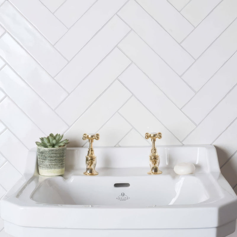 White ceramic sink with gold-toned cross-handle faucets and subtle logo in the Arcadian 300mm Brick collection.