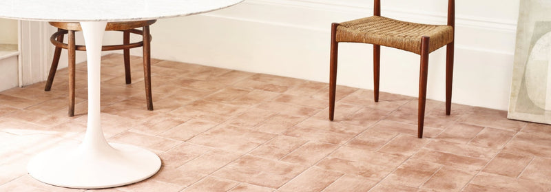 White tulip-style table with smooth glossy surface and slender wooden legs in arcilla terracotta effect tiles collection
