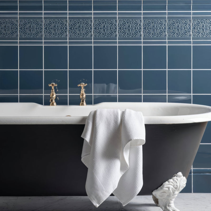 A classic black clawfoot bathtub with gold faucets and a white towel from artworks ascot blue collection