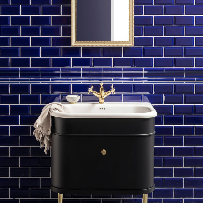 Black ceramic sink with gold faucet and drawer knob set against navy blue tiled wall in artworks royal blue collection