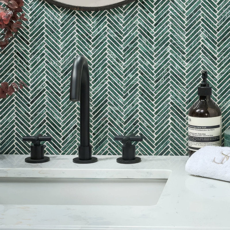 Black matte faucet with two cross-handle knobs against green athens marble mosaic herringbone tile backsplash