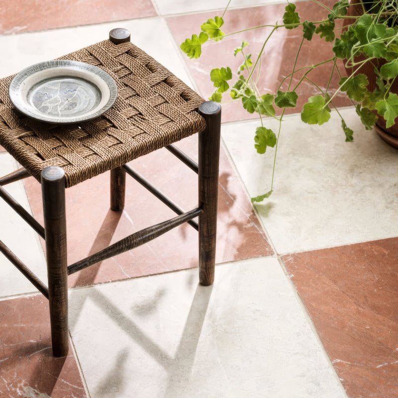 Woven brown rope stool with dark wooden legs and a silver rimmed ceramic plate from Avalon Tumbled Marble collection.
