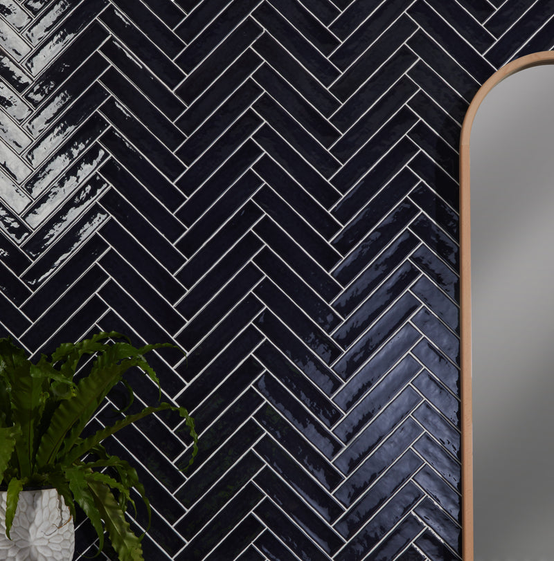 Glossy black ceramic herringbone wall tiles with white grout lines from avebury brick collection
