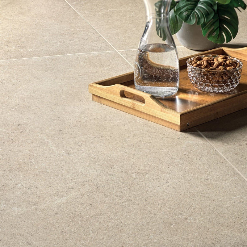 A clear glass carafe filled with water resting on a wooden tray in the axis porcelain tiles collection