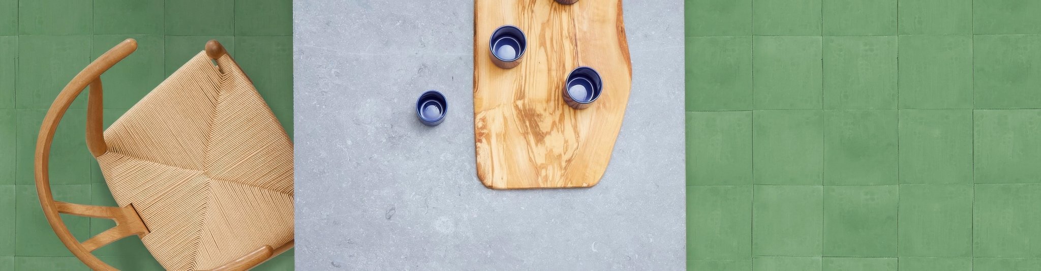 A rustic wooden cutting board with organic shape and visible grain from Bert and May plain tiles collection