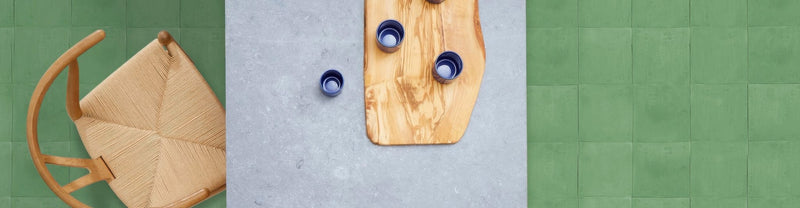 A rustic wooden cutting board with organic shape and visible grain from Bert and May plain tiles collection