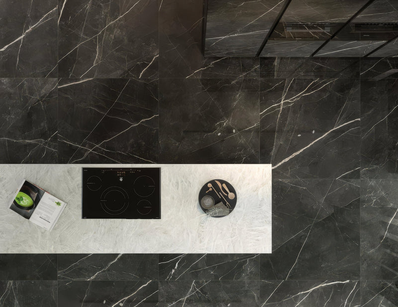Black marble kitchen countertop with white veining and built-in induction cooktop in black floor tiles collection