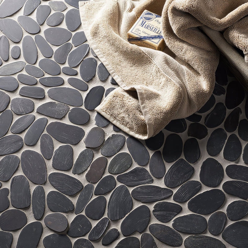 Dark gray smooth stone mosaic floor tiles arranged in a pebble pattern from the black mosaic tiles collection