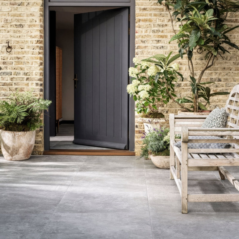 Dark gray vertically paneled front door with a simple brass handle from the bourgogne porcelain tiles collection