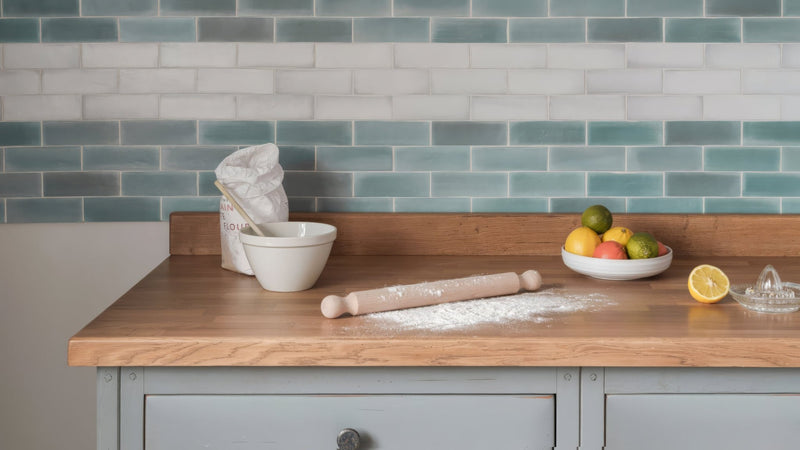 Wooden rolling pin with light-colored finish and flour dusted on surface in a brick kitchen tiles collection