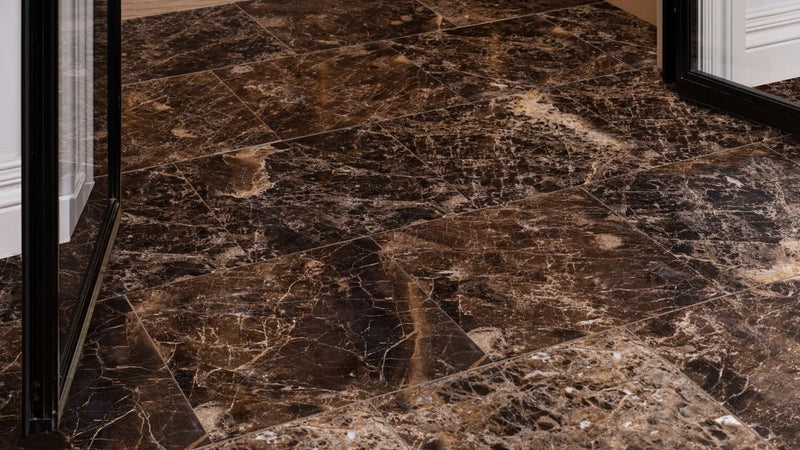 Dark brown marble floor tiles with swirling golden and beige veining from the brown tiles collection