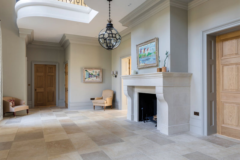 White marble fireplace with ornate mantel and black interior from Ca’Pietra indoor stone tiles collection