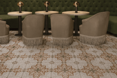 Beige upholstered armchairs with fringe detailing complementing ceramic floor tiles in a stylish living room setting