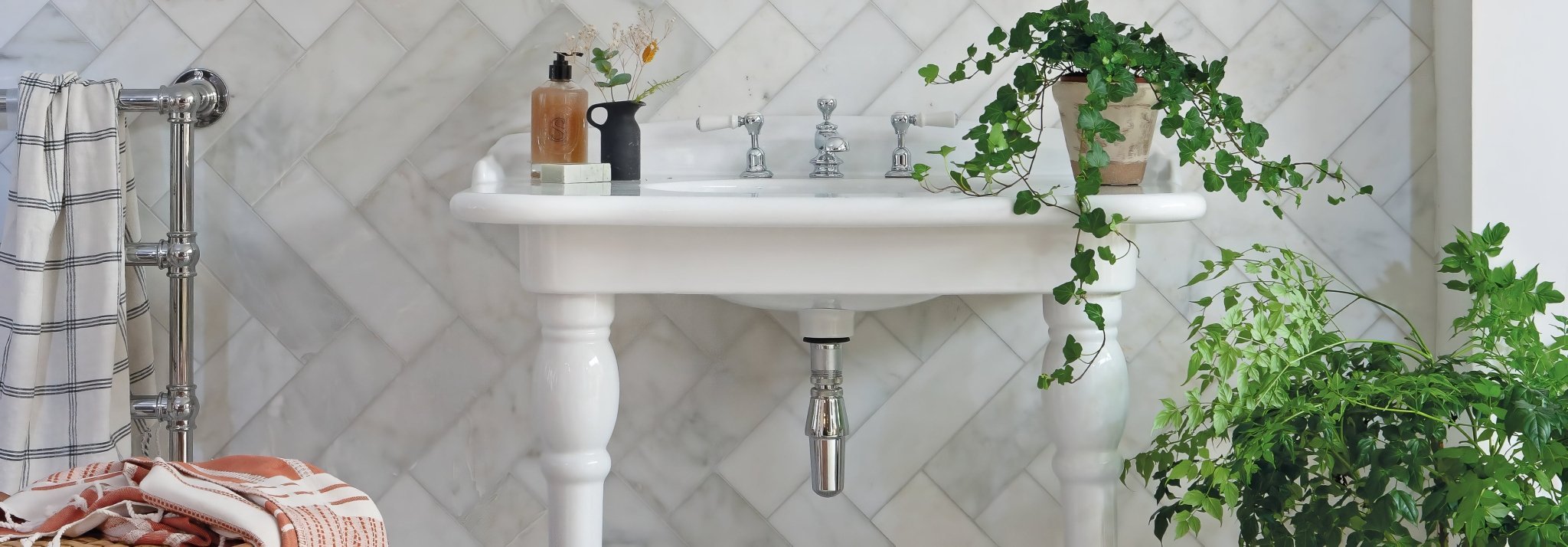 White ceramic pedestal sink with silver fixtures and classic ornate design from the east hampton collection