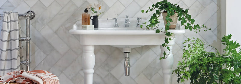 White ceramic pedestal sink with silver fixtures and classic ornate design from the east hampton collection