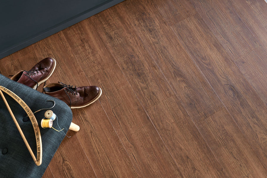 Brown leather lace-up shoes with light-colored sole on engineered wood flooring next to denim fabric and sewing supplies