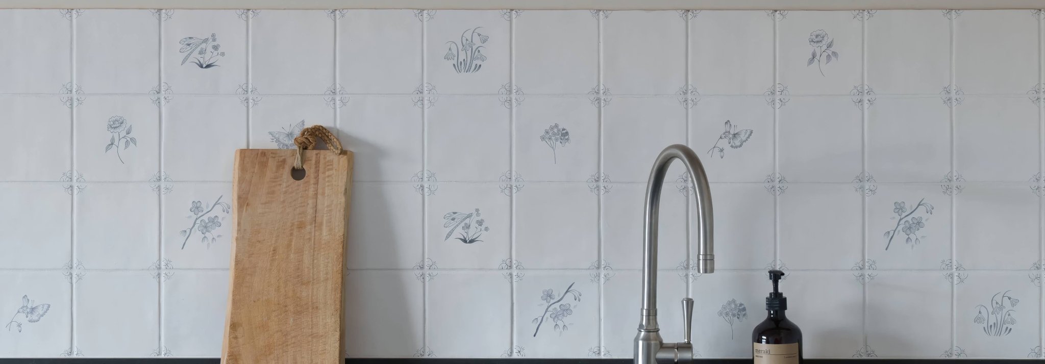 A sleek modern kitchen faucet with polished chrome finish and elegant curved spout in english delft tiles setting