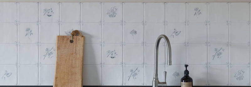 A sleek modern kitchen faucet with polished chrome finish and elegant curved spout in english delft tiles setting