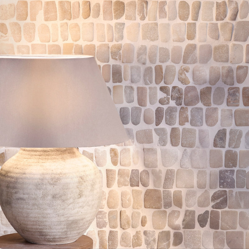 A rustic off-white ceramic table lamp with a textured handcrafted base and soft gray fabric shade from enso cobble mosaic.