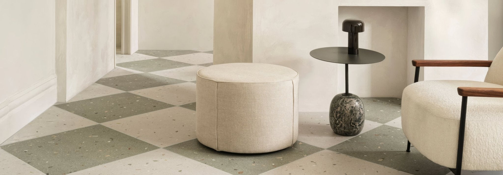 Cream-colored cylindrical pouf with soft textured fabric upholstery from the fired earth floor tiles collection.