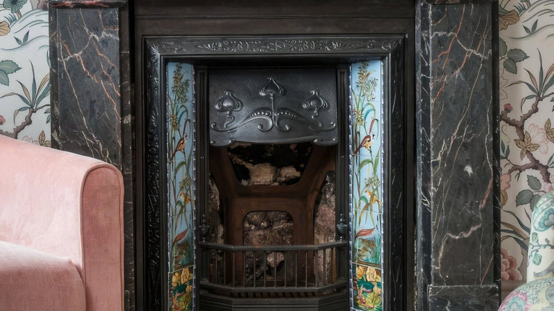Antique black iron fireplace with ornate scrollwork and colorful floral tile accents in fireplace wall tiles collection.