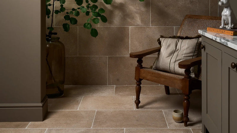 A rustic wooden armchair with a woven cane back and striped upholstered seat cushion in flagstone wall tiles collection.