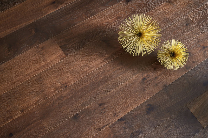Two golden spiky spherical decorative objects on a dark brown wooden floor in a flooring collection