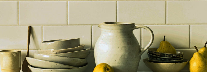 Cream-colored ceramic pitcher with sturdy handle and subtle speckled texture from giralda tile collection.