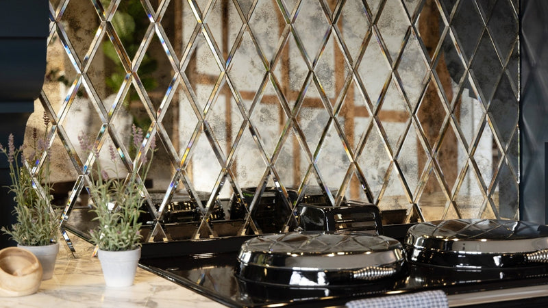 Shiny black stovetop with diamond-patterned mirrored glass wall tiles backsplash in kitchen setting