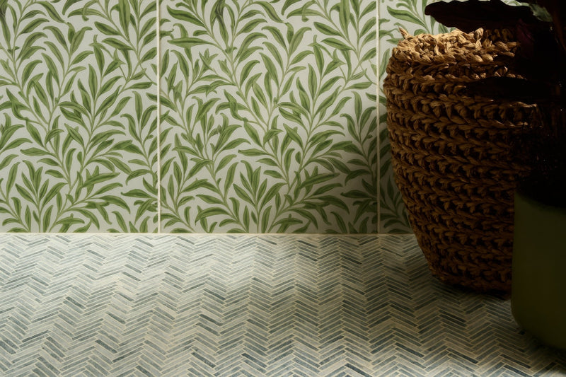 Green leaf-patterned ceramic wall tiles paired with gray and white herringbone mosaic floor tiles in bathroom collection