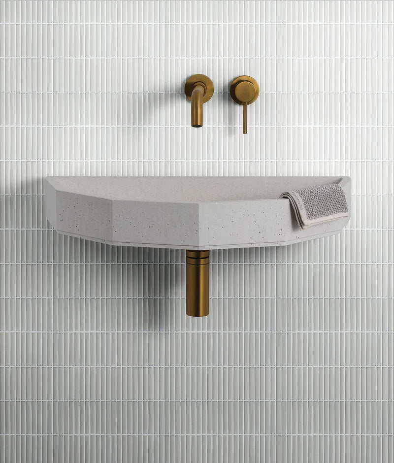 Modern concrete sink with matte gray finish and subtle speckles paired with brushed brass fixtures in grey mosaic tiles collection