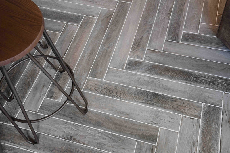 Gray wood-grain tiles arranged in a herringbone pattern from the grey tiles collection