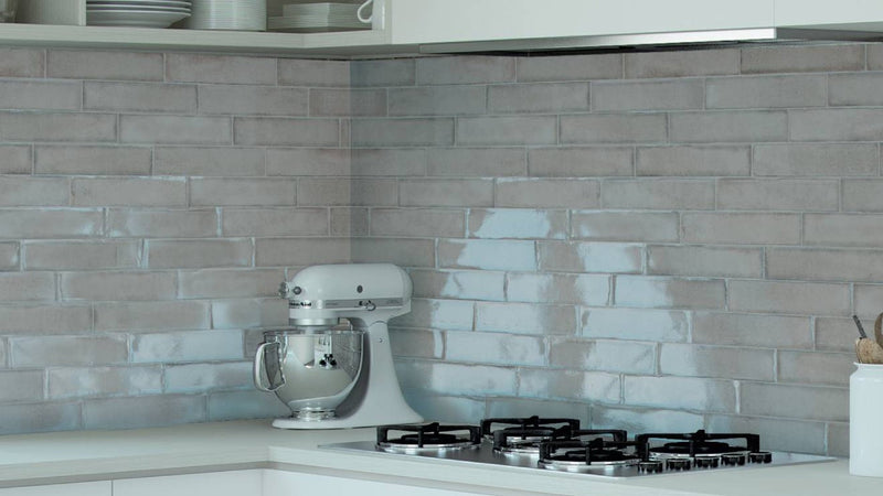 White stand mixer with stainless steel bowl displayed against grey wall tiles background