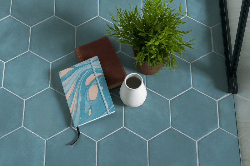 A blue and beige marbled notebook with a black elastic band featured in a hexagon floor tiles collection