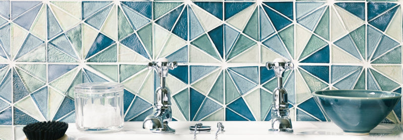 Chrome-finished vintage-style kitchen faucets with cross handles sit symmetrically on a white countertop iridescent glass mosaics collection