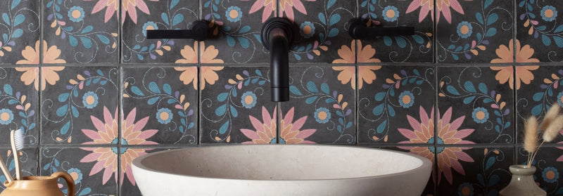 Black matte-finished faucet with curved spout and handle mounted above white ceramic sink against kelmscott tile collection floral tiles
