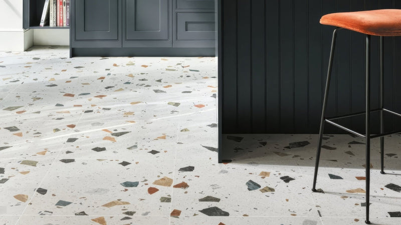 Terrazzo kitchen floor tiles with light gray base and colorful stone fragments in black brown orange green and beige