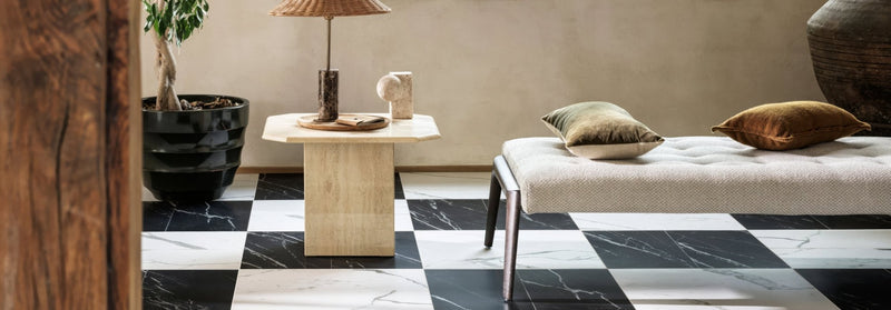 A sleek modern bench with tufted off-white upholstery and slender metallic legs in the Lucca marble effect tile collection.