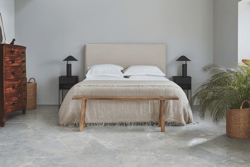 Beige upholstered bed with minimalist design and wooden legs displayed on lvt floor tiles collection