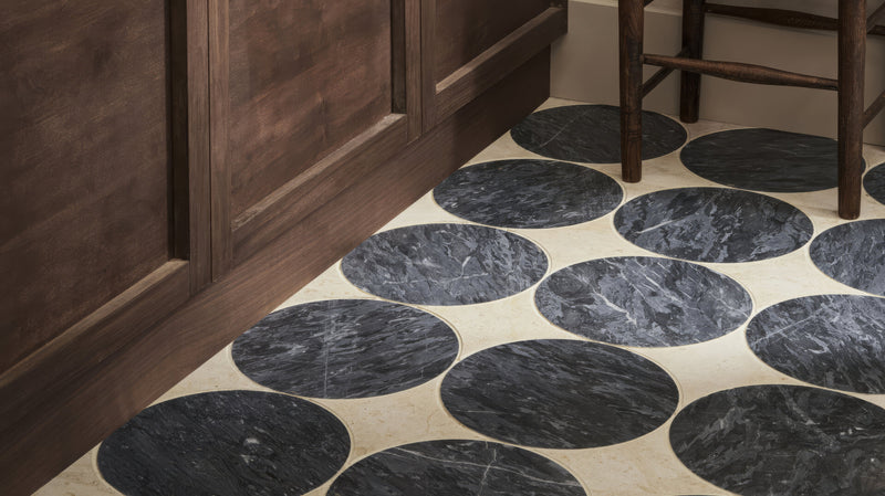 Dark gray circular marble kitchen tiles with subtle veining on a light beige floor showcasing marble material quality