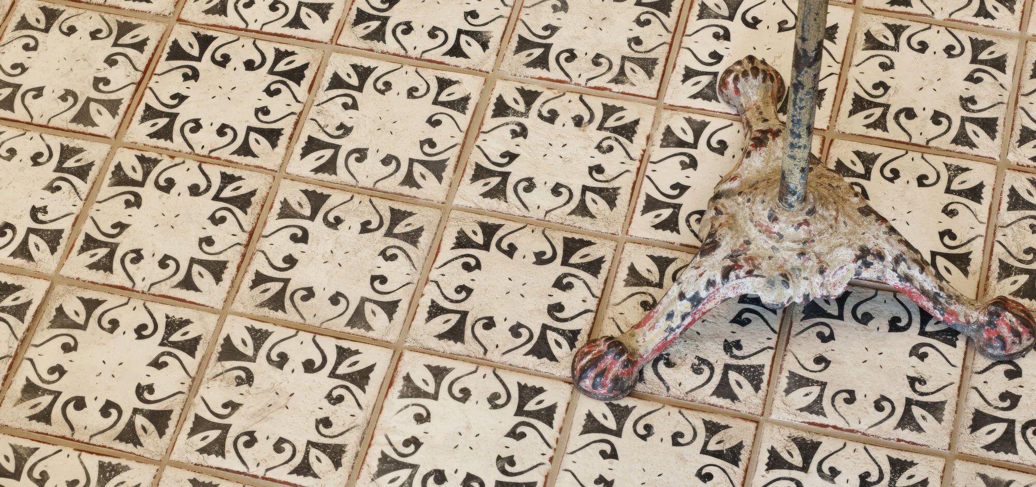 Weathered bronze cast iron table leg with ornate scrollwork from the marrakech tile collection