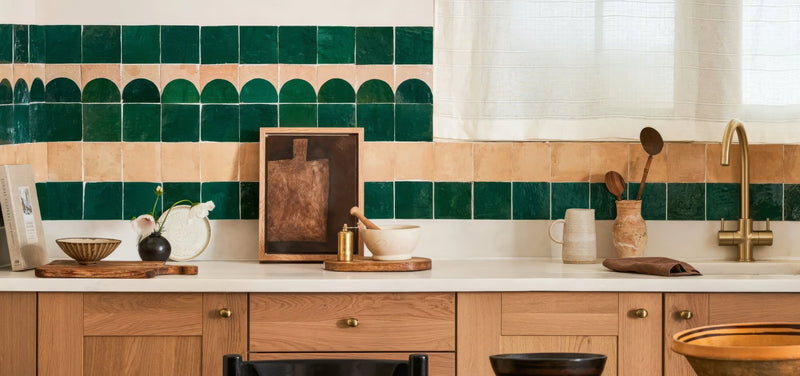 The kitchen backsplash from the Medina Tile Collection features deep green and warm beige scalloped banded tiles.