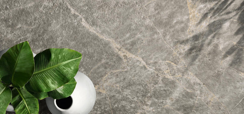 White ceramic vase holding lush green leaves featured in minoli tiles collection for stylish home decor