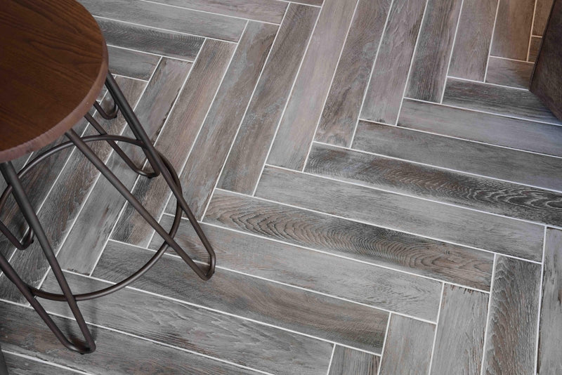 Gray wood-grain tiles from minoli wood look tiles collection arranged in a herringbone pattern for flooring and walls